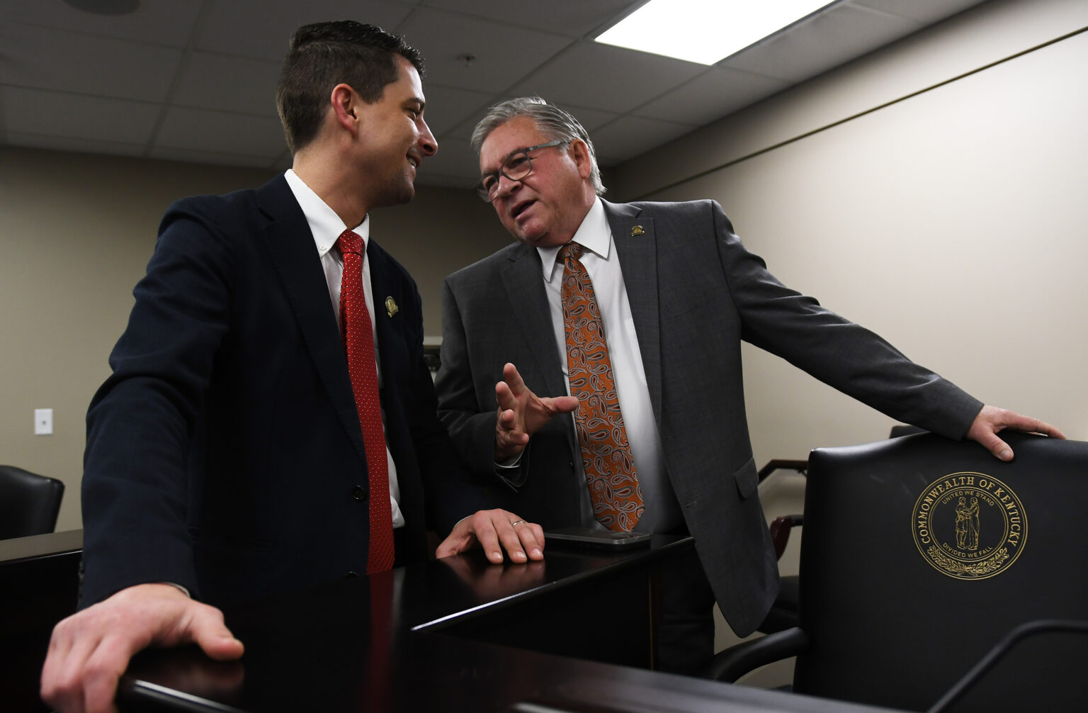 Bridges wears an orange tie as he speaks with Justice, who wears a red tie.